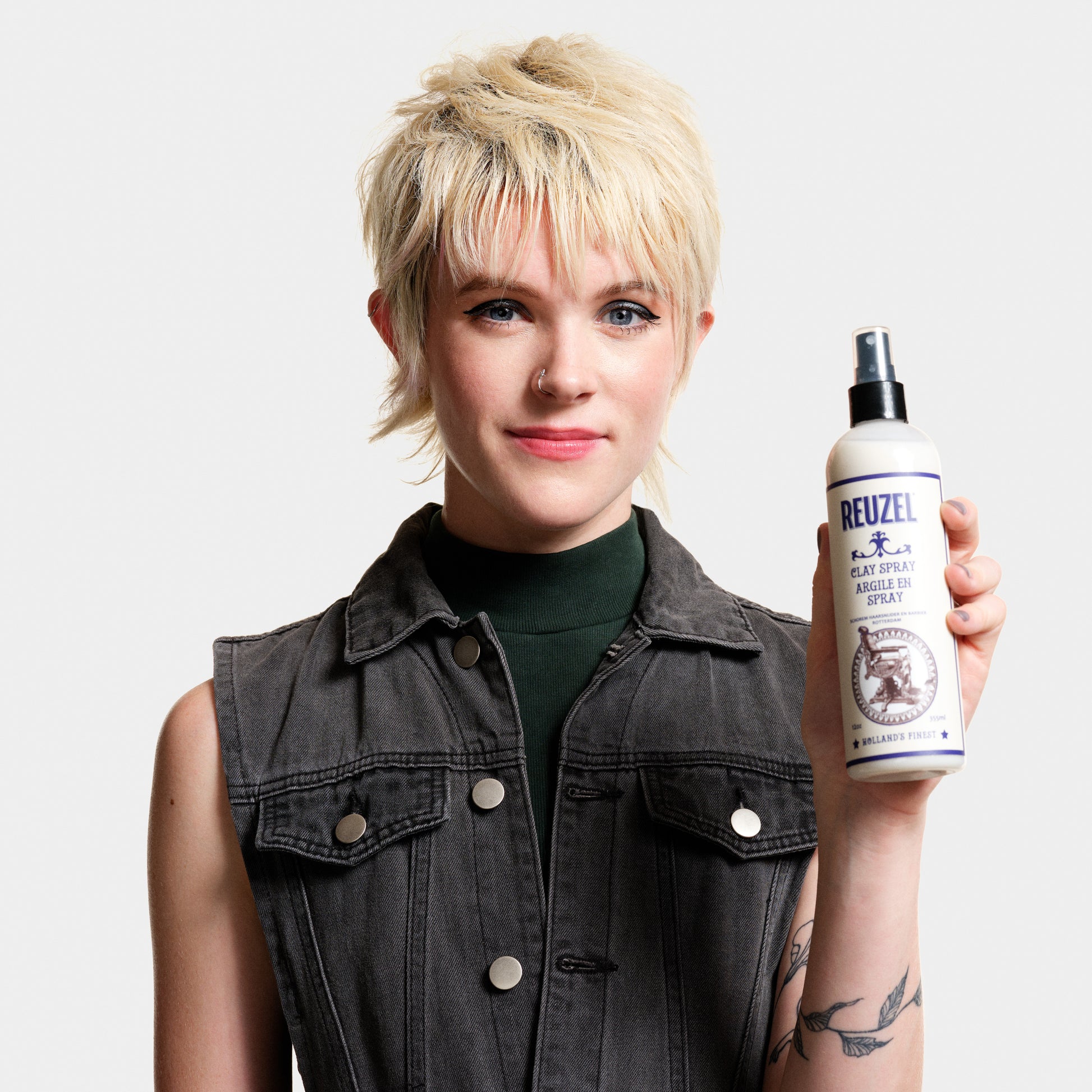 Reuzel Clay Spray hair styling product in a spray bottle, designed for textured, matte finish styling.