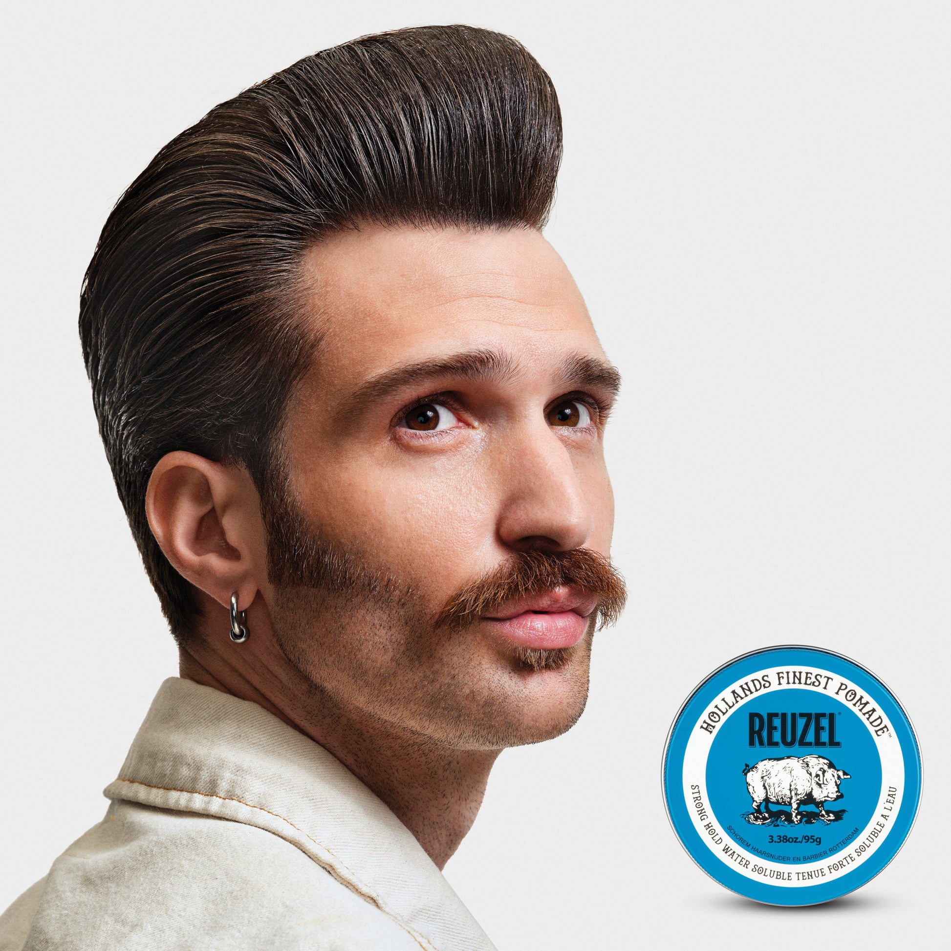 Reuzel Road Trip To Go Blue Pomade jar with blue label and lid, showcasing the hair styling pomade product.