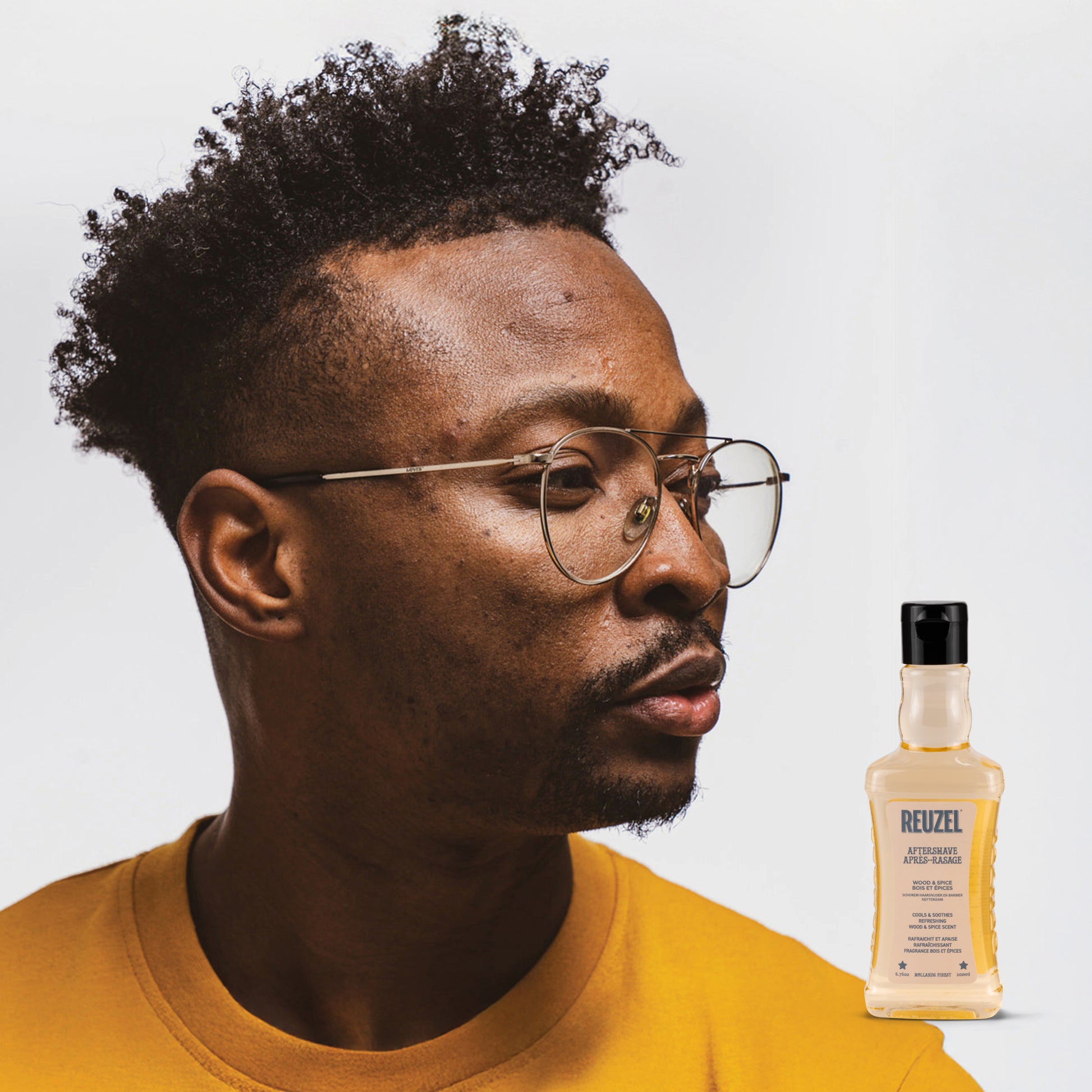 Reuzel Aftershave Wood & Spice in a glass bottle with a black cap, featuring a woody and spicy scent for beard grooming.