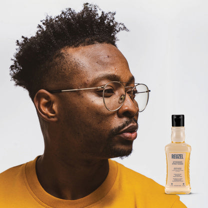Reuzel Aftershave Wood & Spice in a glass bottle with a black cap, featuring a woody and spicy scent for beard grooming.