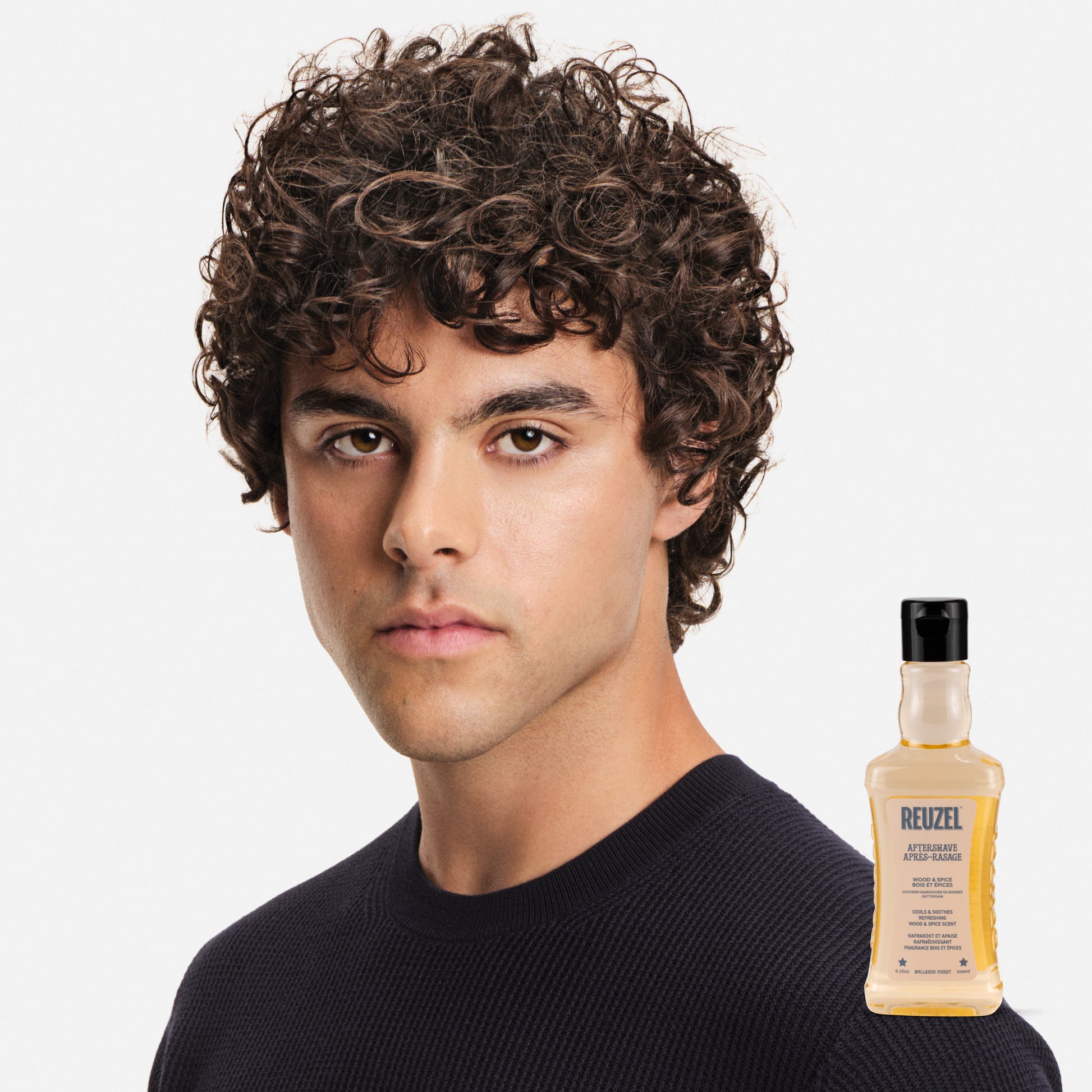Reuzel Wood & Spice beard aftershave bottle with a dark wood and spice label, showcasing natural grooming product for men.