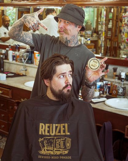 Reuzel X Liquid Death Severed Head barber cape featuring graphic print, designed for professional grooming and barber use.